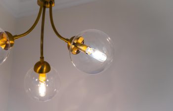 A close-up of a modern ceiling light fixture with glass globes and glowing LED bulbs.